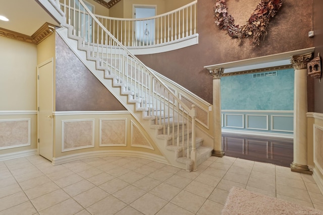 4931 Peggy St, West Bloomfield, MI 48322 - stairway featuring tile patterned floors, a towering ceiling, a decorative wall, crown molding, and a wainscoted wall
