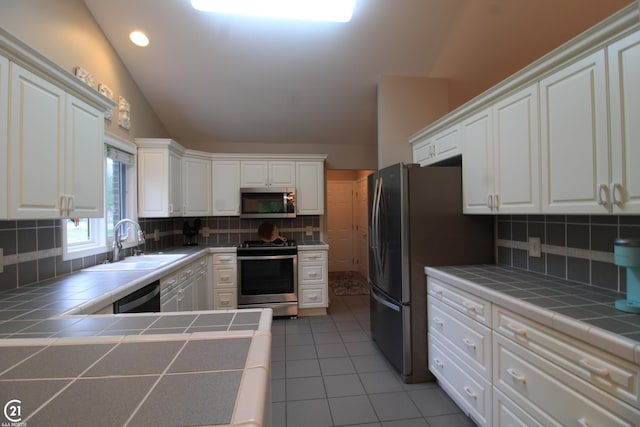 50887 Nature Dr, New Baltimore, MI 48047 - kitchen featuring appliances with stainless steel finishes, tile countertops, lofted ceiling, tasteful backsplash, and white cabinetry