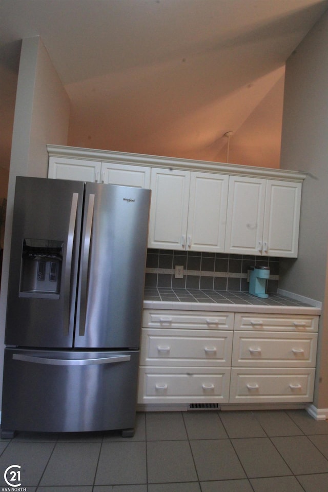 50887 Nature Dr, New Baltimore, MI 48047 - kitchen featuring stainless steel fridge with ice dispenser, tile countertops, vaulted ceiling, white cabinetry, and tile patterned floors