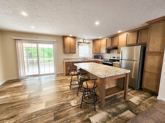 2521 Bonnie Mae Rd, Harrison, MI 48625 - kitchen with appliances with stainless steel finishes, wood finished floors, baseboards, a sink, and under cabinet range hood