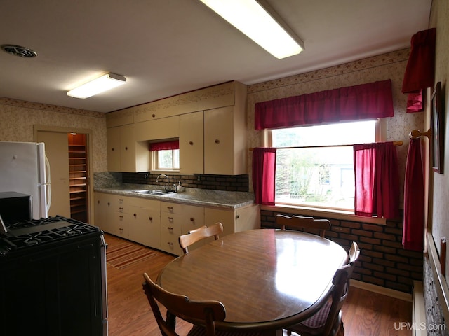 50 Baltic Ave, South Range, MI 49963 - kitchen with wallpapered walls, freestanding refrigerator, range with gas cooktop, a sink, and light wood finished floors