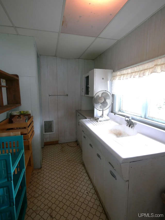 50 Baltic Ave, South Range, MI 49963 - kitchen with white cabinets, light countertops, wood walls, a drop ceiling, and a sink
