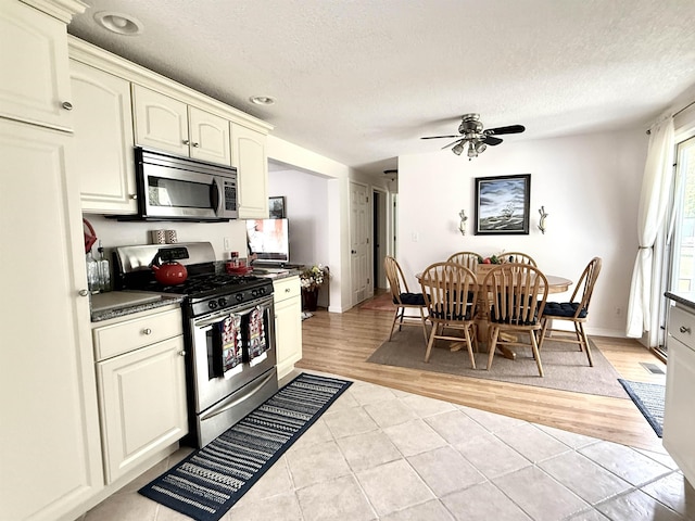 2684 Lakeshore Dr, Gladwin, MI 48624 - kitchen featuring appliances with stainless steel finishes, dark countertops, light tile patterned floors, a textured ceiling, and ceiling fan