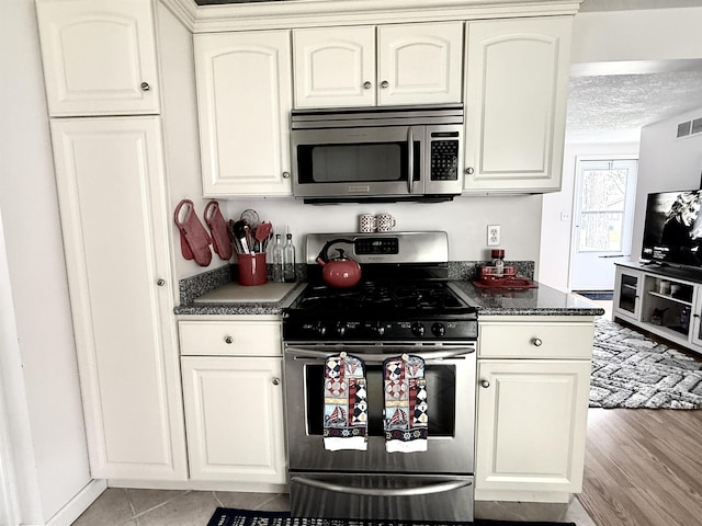 2684 Lakeshore Dr, Gladwin, MI 48624 - kitchen featuring stainless steel appliances, dark countertops, white cabinetry, and a textured ceiling