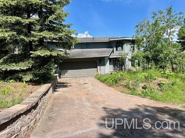 9411 Goodell Rd, Eagle Harbor, MI 49950 - view of front of house featuring driveway, a garage, and stucco siding