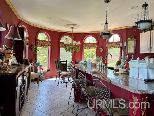 9411 Goodell Rd, Eagle Harbor, MI 49950 - kitchen with a chandelier, crown molding, a kitchen bar, dark stone counters, and stone tile flooring