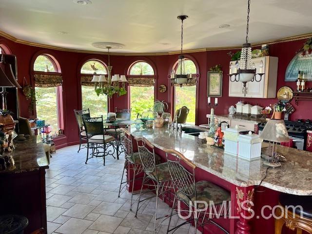 9411 Goodell Rd, Eagle Harbor, MI 49950 - kitchen with stone tile floors, a breakfast bar, light stone countertops, hanging light fixtures, and ornamental molding