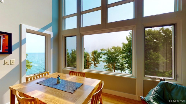 N9910 Shore Dr, Au Train, MI 49806 - dining room with a water view, a towering ceiling, plenty of natural light, and light wood-style flooring