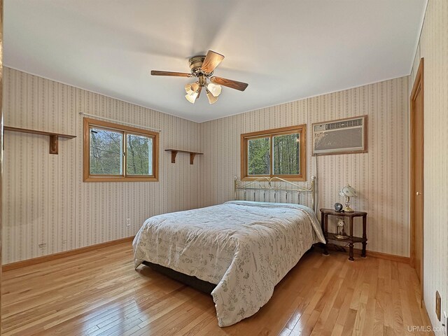 8672 M.5 Rd, Gladstone, MI 49837 - bedroom featuring light wood-type flooring, a wall mounted air conditioner, a ceiling fan, and baseboards