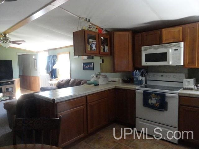 2801 M-94 Hwy, Eben Junction, MI 49825 - kitchen with white appliances, a peninsula, tile counters, a ceiling fan, and glass insert cabinets