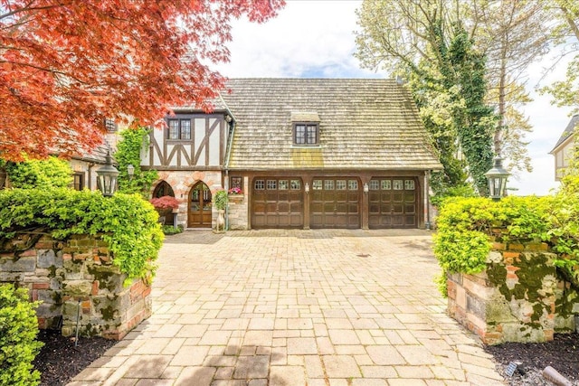 49016 Pointe Lakeview Dr, Chesterfield, MI 48047 - tudor-style house featuring decorative driveway, stone siding, and a garage