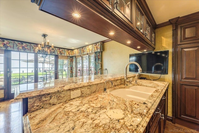 49016 Pointe Lakeview Dr, Chesterfield, MI 48047 - kitchen featuring a sink, light stone countertops, a chandelier, decorative light fixtures, and dark brown cabinets