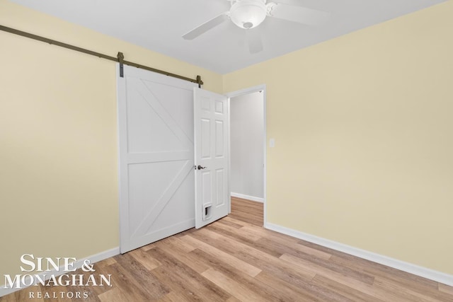 22574 Katzman St, Clinton Township, MI 48035 - unfurnished bedroom with baseboards, light wood-style flooring, and a barn door