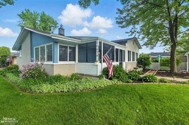 22574 Katzman St, Clinton Township, MI 48035 - view of side of home featuring a sunroom, brick siding, a chimney, and a yard