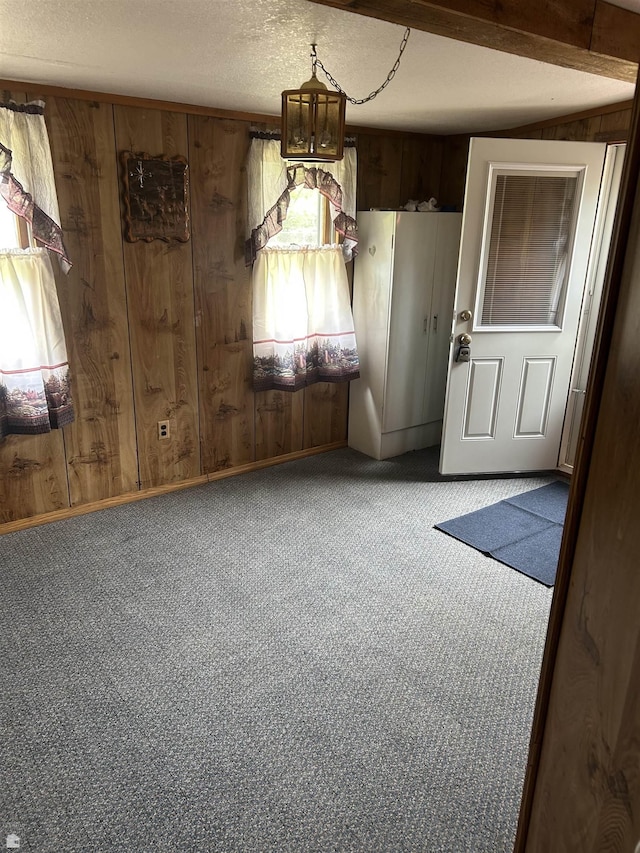 1923 Bear Dr, Oscoda, MI 48750 - unfurnished dining area featuring wood walls, carpet, plenty of natural light, and a textured ceiling