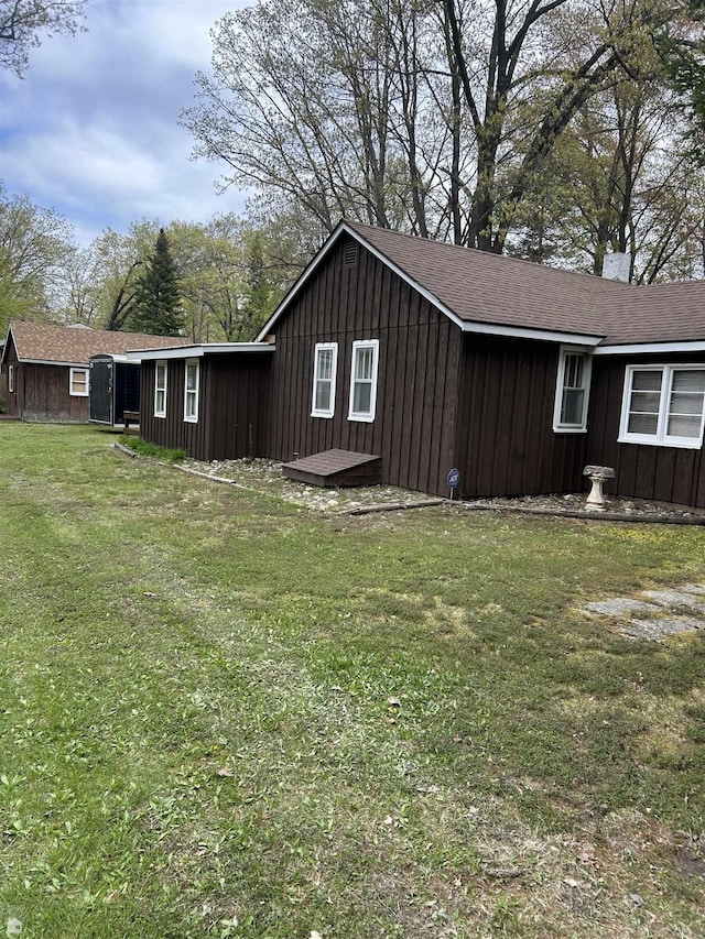 1923 Bear Dr, Oscoda, MI 48750 - view of side of home featuring a lawn and board and batten siding