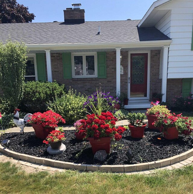 5149 Reinhardt Ln, Bay City, MI 48706 - view of exterior entry featuring brick siding, a chimney, and a porch