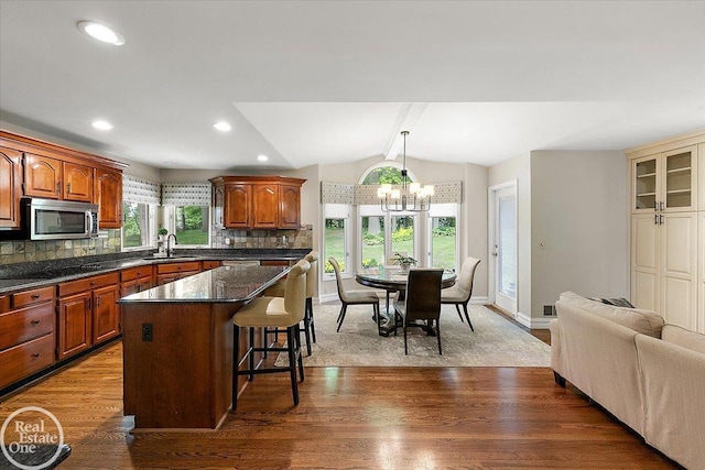 63011 Indian Hills Dr Unit # 1, Washington Twp, MI 48095 - kitchen featuring stainless steel microwave, a sink, a breakfast bar, backsplash, and a chandelier
