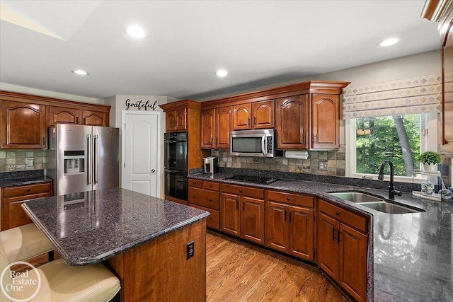 63011 Indian Hills Dr Unit # 1, Washington Twp, MI 48095 - kitchen featuring black appliances, a sink, a kitchen breakfast bar, backsplash, and light wood-style floors