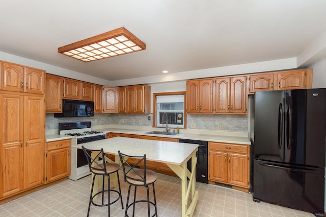 205 E Murphy St, Bay City, MI 48706 - kitchen with black appliances, a sink, light countertops, light floors, and a breakfast bar