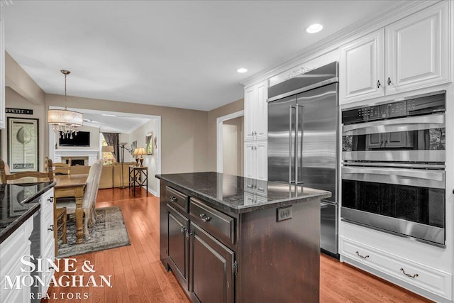 55266 Lordona Ln, Shelby Twp, MI 48315 - kitchen featuring appliances with stainless steel finishes, white cabinetry, dark stone counters, light wood-style flooring, and recessed lighting