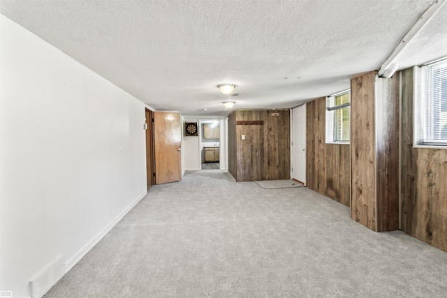 42910 Utica Rd, Sterling Heights, MI 48314 - unfurnished living room featuring a textured ceiling, wood walls, light colored carpet, and baseboards