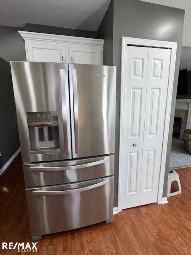 53234 Fox Pointe Dr, New Baltimore, MI 48047 - kitchen view of stainless steel fridge with ice dispenser, wood finished floors, white cabinetry, and a fireplace