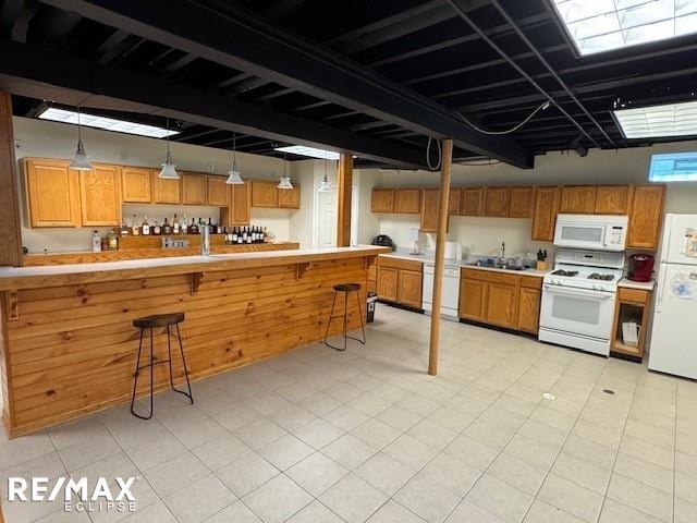 53234 Fox Pointe Dr, New Baltimore, MI 48047 - kitchen featuring white appliances, a breakfast bar area, a sink, light countertops, and brown cabinets