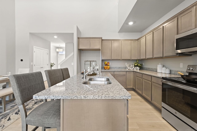 2215 Chase Dr Unit 102, Howell, MI 48855 - kitchen with appliances with stainless steel finishes, a sink, a kitchen breakfast bar, recessed lighting, and light stone counters