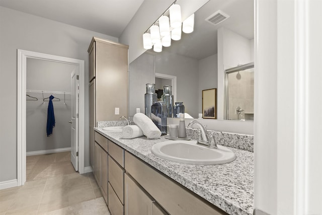 2215 Chase Dr Unit 102, Howell, MI 48855 - full bathroom featuring double vanity, a spacious closet, a shower with door, tile patterned flooring, and baseboards