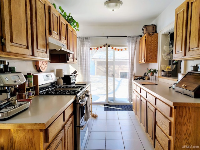 304 E Lincoln St, Negaunee, MI 49866 - kitchen featuring double oven range, under cabinet range hood, light countertops, light tile patterned flooring, and brown cabinets