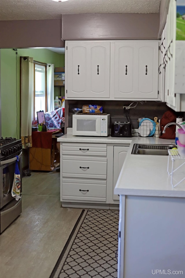 5631 County Road 550th Rd, Marquette, MI 49855 - kitchen featuring white microwave, stainless steel range with gas cooktop, a sink, light countertops, and a textured ceiling