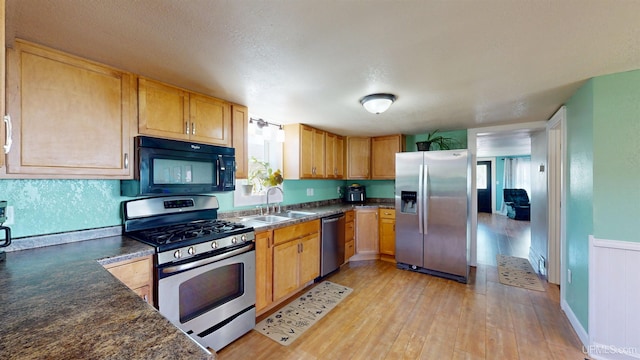 422 Washington St, Ishpeming, MI 49849 - kitchen featuring stainless steel appliances, a sink, dark countertops, and light wood-type flooring