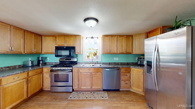 422 Washington St, Ishpeming, MI 49849 - kitchen featuring appliances with stainless steel finishes, a sink, light wood finished floors, and dark countertops