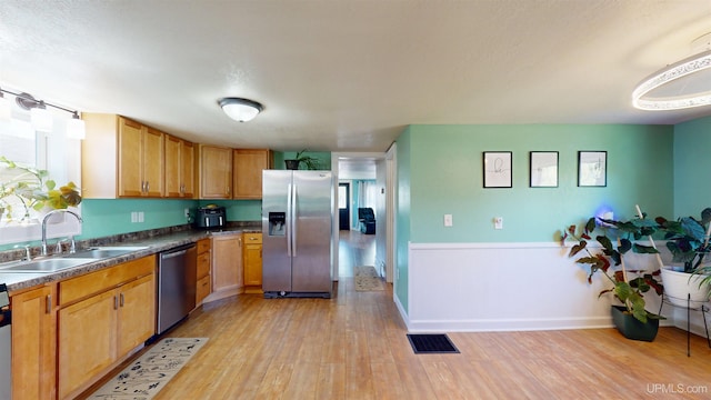 422 Washington St, Ishpeming, MI 49849 - kitchen with stainless steel appliances, a sink, light wood-style flooring, and dark countertops