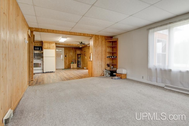 1782 H Rd, Bark River, MI 49807 - unfurnished living room featuring wooden walls, light carpet, baseboards, a baseboard heating unit, and a ceiling fan