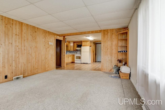 1782 H Rd, Bark River, MI 49807 - unfurnished living room with light carpet, wood walls, a drop ceiling, and baseboards