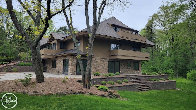 966 Pine Needle Trl, Oakland Twp, MI 48306 - view of front of home with a balcony, stone siding, a patio area, a front lawn, and roof with shingles