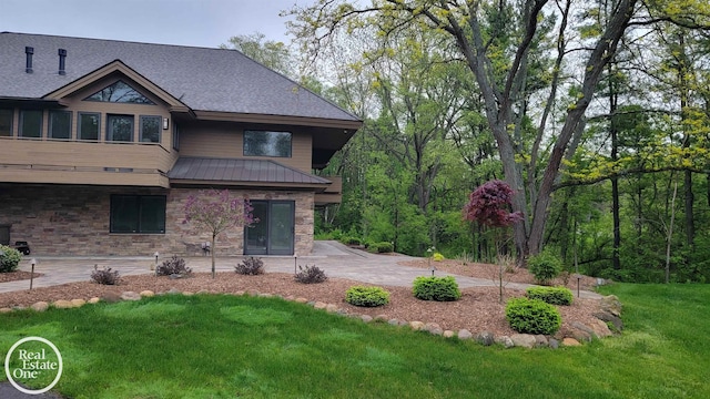 966 Pine Needle Trl, Oakland Twp, MI 48306 - rear view of property featuring a patio, a yard, stone siding, metal roof, and a standing seam roof