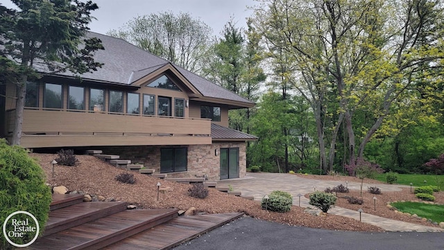 966 Pine Needle Trl, Oakland Twp, MI 48306 - rear view of property featuring a patio, stone siding, and metal roof