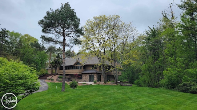 966 Pine Needle Trl, Oakland Twp, MI 48306 - rear view of property with a yard, a standing seam roof, stone siding, and metal roof