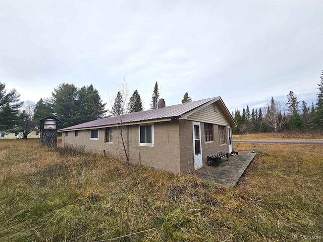 10162 Wyoming Rd, Mohawk, MI 49918 - view of property exterior with concrete block siding, metal roof, and a chimney