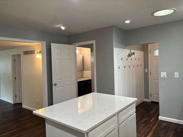 3214 Elnor Dr, Gladwin, MI 48624 - kitchen with dark wood-style floors, baseboards, light stone counters, white cabinetry, and a kitchen island