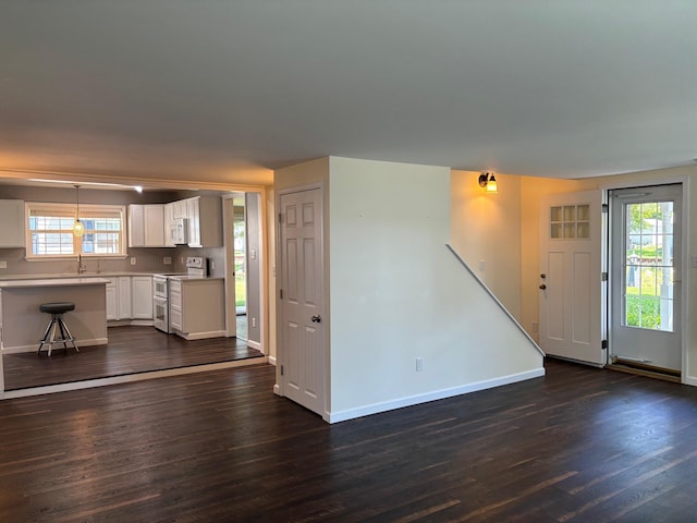 3214 Elnor Dr, Gladwin, MI 48624 - unfurnished living room featuring dark wood-style flooring, baseboards, and a sink