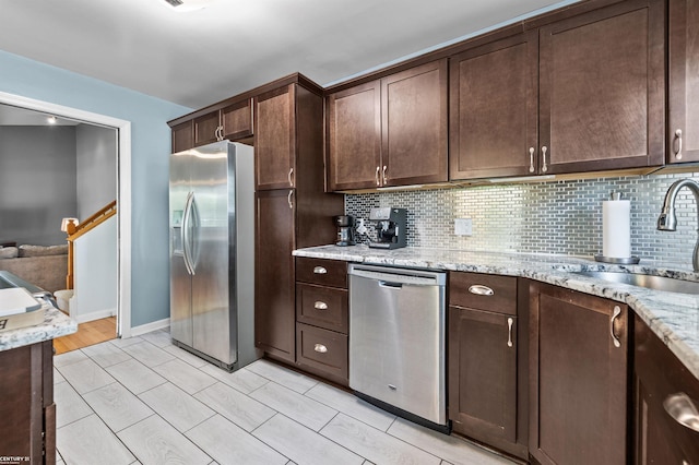 8912 Hubbard St, Livonia, MI 48150 - kitchen with appliances with stainless steel finishes, a sink, dark brown cabinets, backsplash, and light stone counters