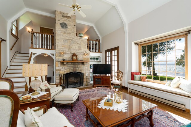 7975 00.25 Rd, Garden, MI 49835 - living room with ceiling fan, wood finished floors, a stone fireplace, a baseboard radiator, and stairway