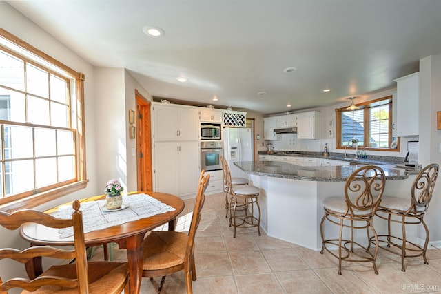 7975 00.25 Rd, Garden, MI 49835 - kitchen with appliances with stainless steel finishes, a peninsula, under cabinet range hood, a kitchen breakfast bar, and recessed lighting