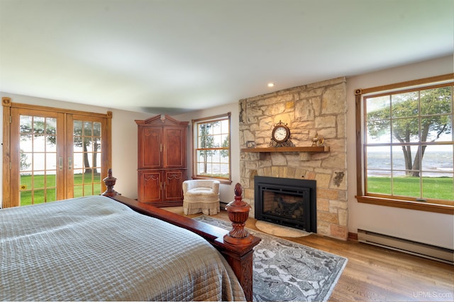 7975 00.25 Rd, Garden, MI 49835 - bedroom with a fireplace, access to outside, light wood-style flooring, and a baseboard radiator