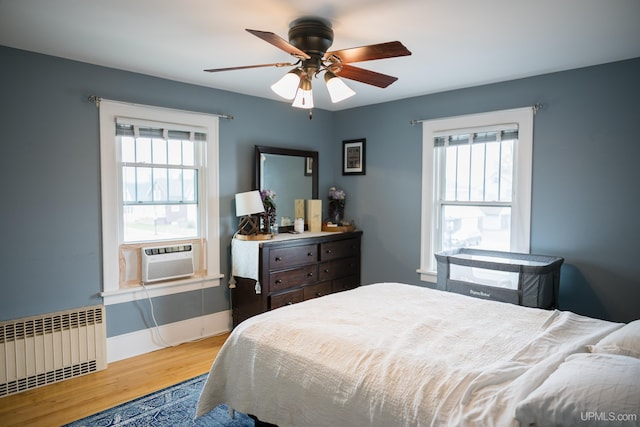 1302 N 3rd St, Ishpeming, MI 49849 - bedroom with radiator heating unit, wood finished floors, multiple windows, and cooling unit