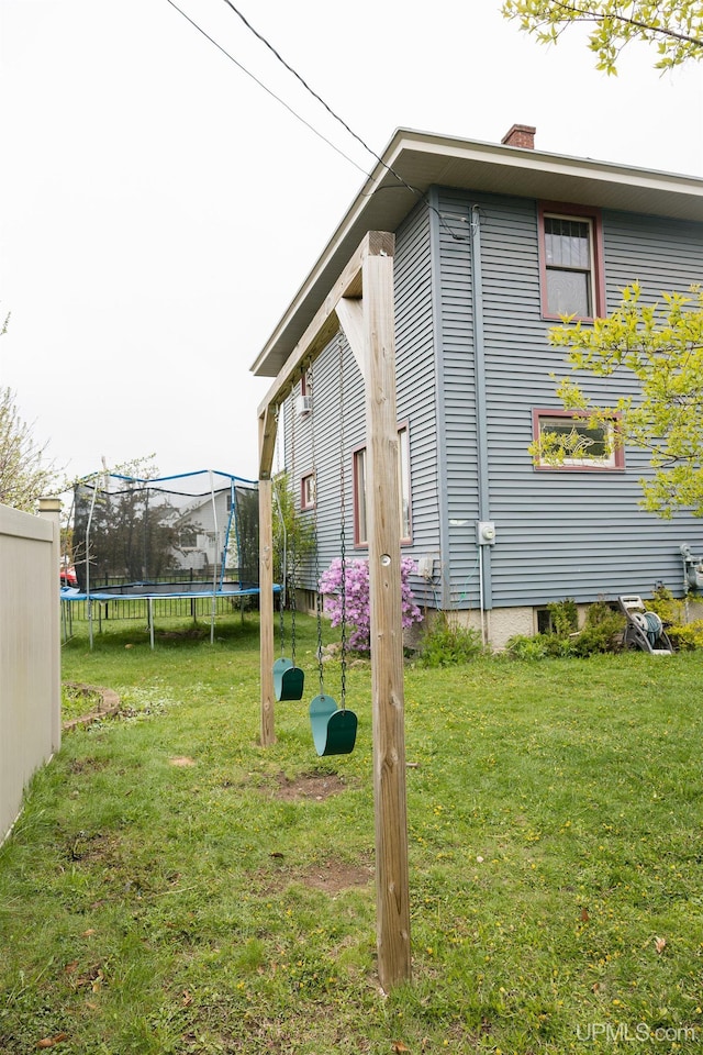 1302 N 3rd St, Ishpeming, MI 49849 - view of side of property with a trampoline, a yard, and a chimney